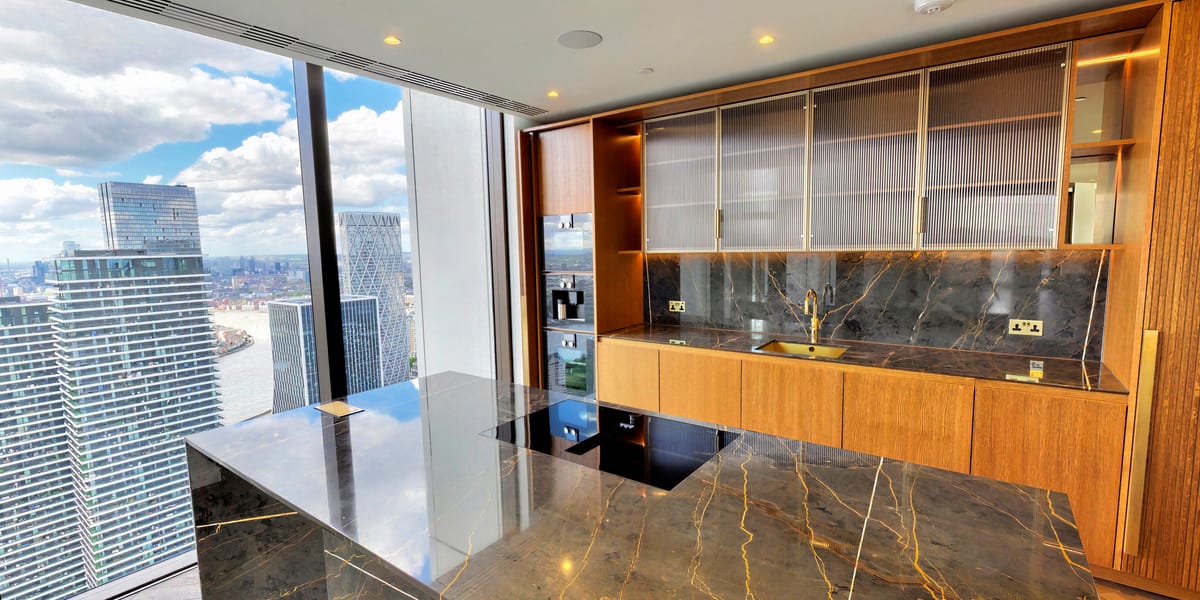 Curved dark marble kitchen island with warm wood cabinetry and city views beyond